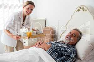 Portrait of female doctor serving food to senior patient relaxing on bed