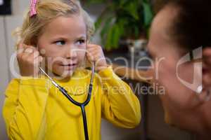 Little girl using stethoscope in hospital