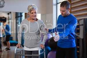 Man helping senior woman to walk with walker