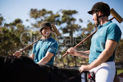 Two male jockeys riding horse in the ranch