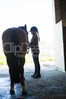 Teenage girl standing with horse