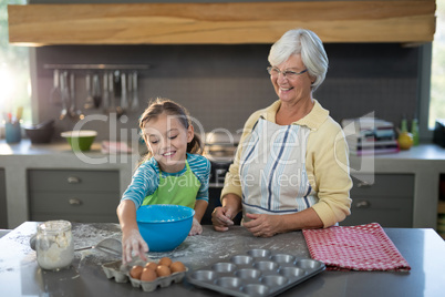 Granddaughter picking up eggs and grandmother smiling