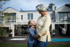 Smiling grandmother and granddaughter embracing each other in garden