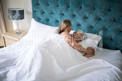 Granddaughter talking to grandmother on bed