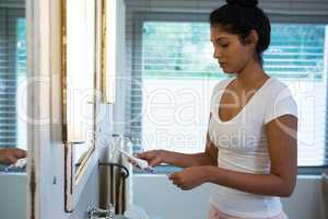 Woman holding toothbrush in bathroom