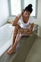 Full length of young woman shaving leg