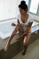 Woman by bathtub shaving leg