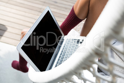 Low section of woman using laptop on swing