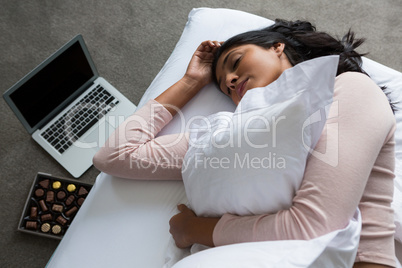 Woman sleeping on bed over floor