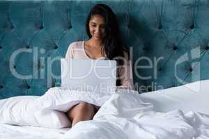 Woman using laptop on bed