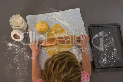 High angle view of boy rolling dough