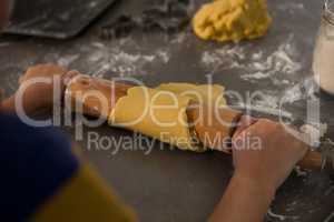 Cropped hands of boy rolling dough