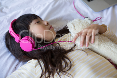 Girl listening to music while resting on bed