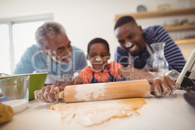 Boy preparing cookie dough with his father and grandfather in kitchen