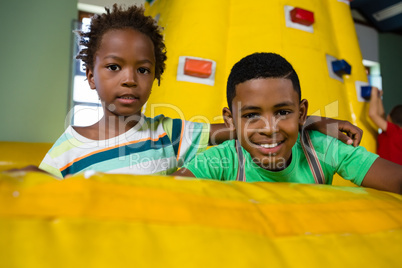 Portrait of friends with arm around sitting on bouncy castle