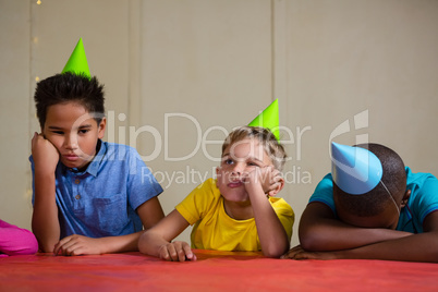 Bored children wearing party hat at table