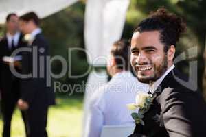 Portrait of handsome groomsman smiling in park