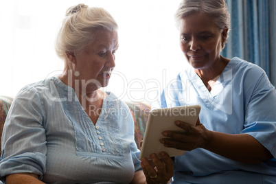 Doctor showing digital table to senior woman