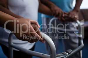 Cropped hands of nurse assisting woman in walking with walker