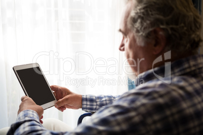 Side view of senior man using digital tablet in nursing home