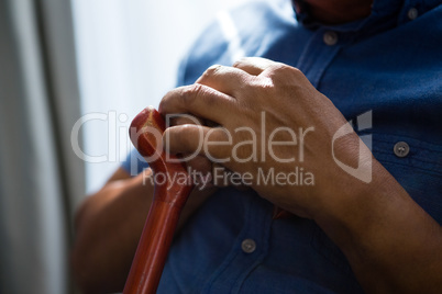 Midsection of senior man holding walking cane at nursing home