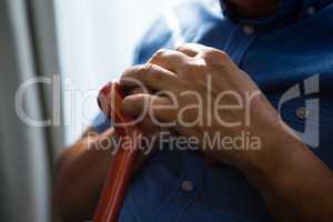 Midsection of senior man holding walking cane at nursing home