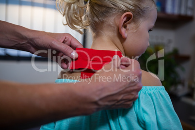 Physiotherapist sticking tape on girl patient