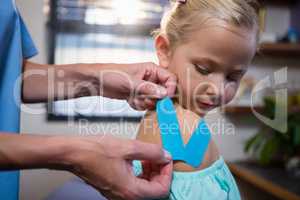 Physiotherapist sticking tape on girl patient