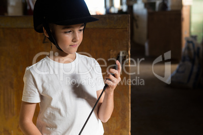 Girl holding crop stick in stable
