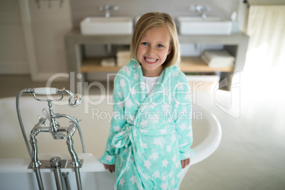 Smiling girl standing near bathtub in bathroom