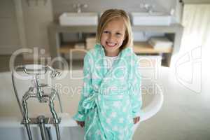 Smiling girl standing near bathtub in bathroom