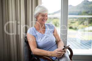 Smiling senior woman using mobile phone on chair