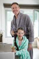 Smiling father and daughter holding toothbrush in bathroom