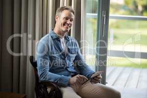 Smiling man using digital tablet on chair