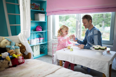 Girl pouring tea for her father from the toy kitchen set