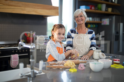 Grandmother and granddaughter posing holding dough