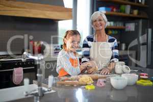 Grandmother and granddaughter posing holding dough