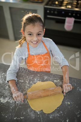 Little girl flattening dough on the kitchen counter