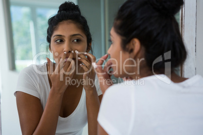 Woman squeezing pimple reflecting on mirror