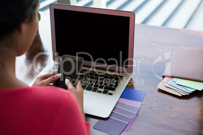 Woman with laptop using phone