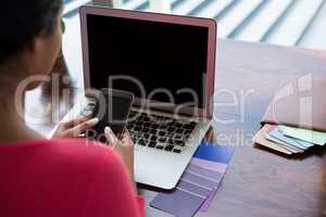Woman with laptop using phone