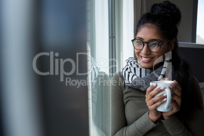 Smiling woman with coffee cup by window