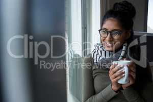 Smiling woman with coffee cup by window