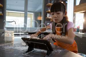 Girl using digital tablet in kitchen