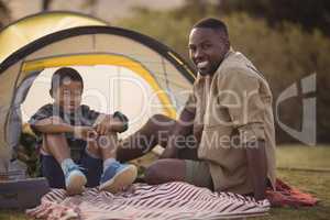 Father and son sitting on a blanket in park