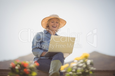 Smiling senior woman using laptop in park