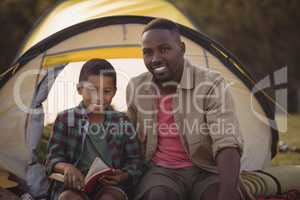 Happy father and son reading book in park