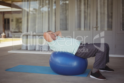 Senior man doing stretching exercise on exercise ball