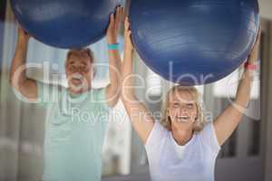 Smiling senior couple exercising with exercise ball