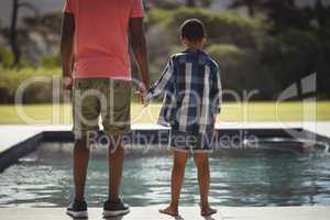 Father and son standing near poolside